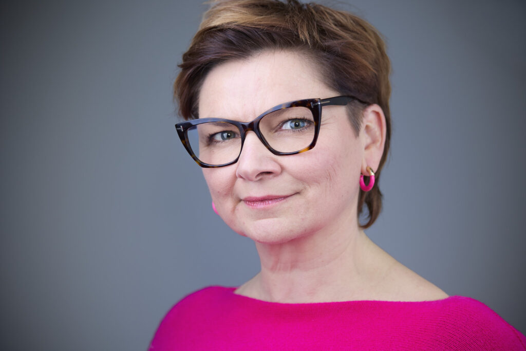 Frau mit pinken Oberteil und keckem Blick