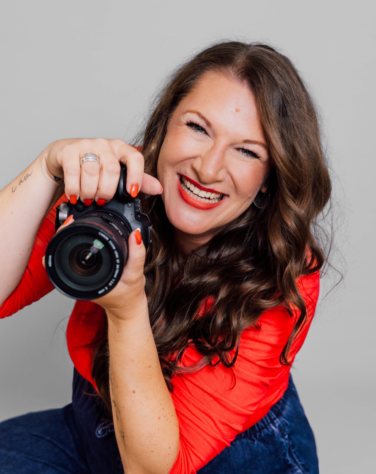 Ines Schäfer, SEELENfotogräfin®, lacht mit ihrer Kamera in der Hand